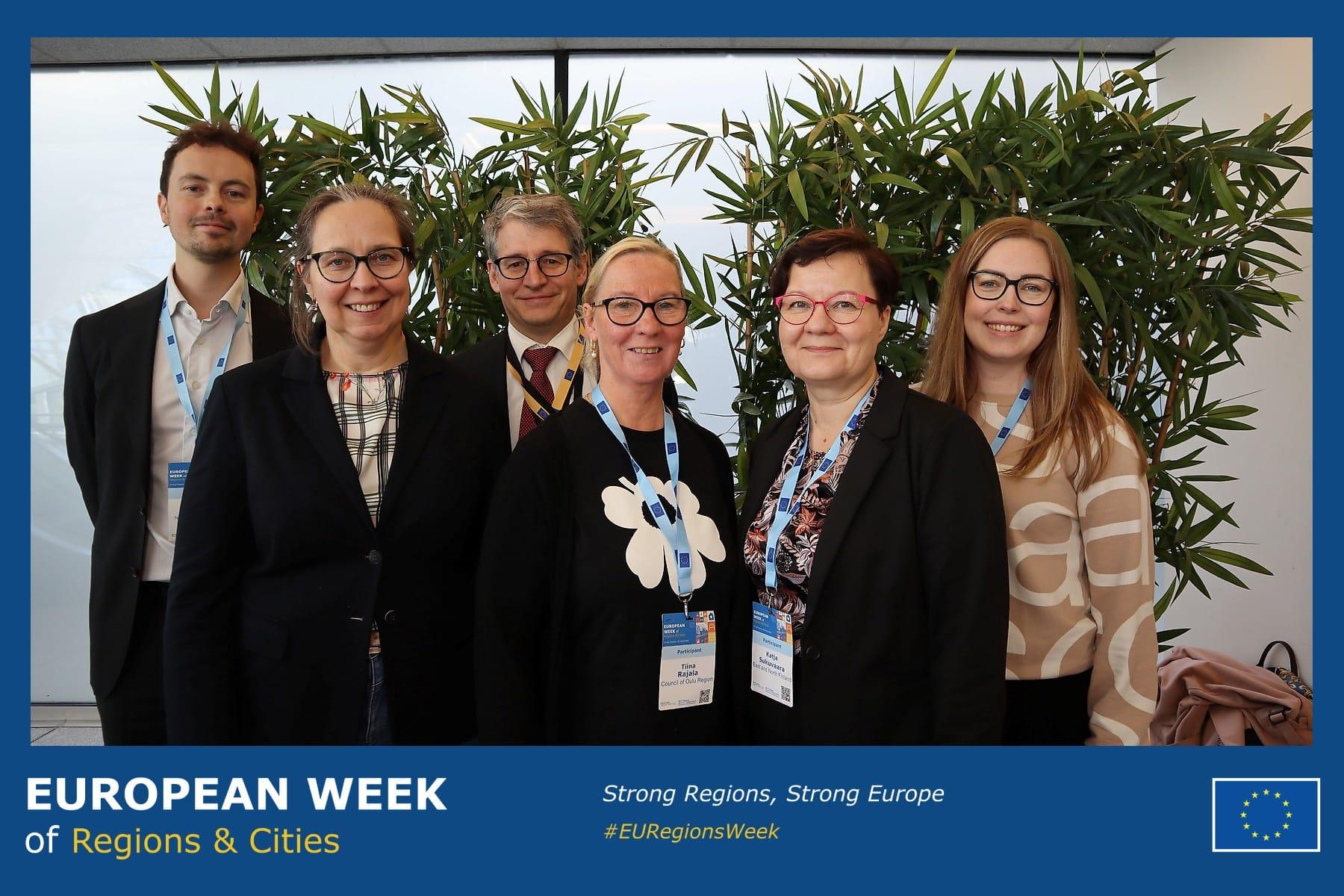 Ryhmäkuvassa kuusi ihmistä rivissä. Ympärillä sininen kehys, jossa lukee European week of regions and cities. Strong regions, strong europe.